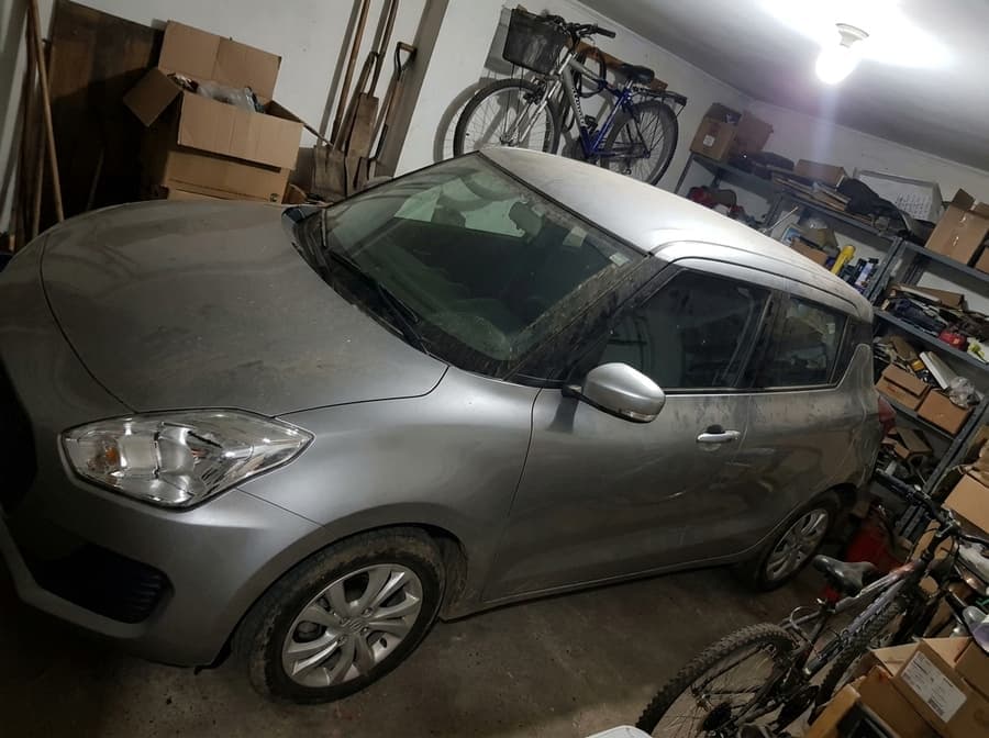 Ejemplo de foto mala para vender un auto: garaje oscuro y desordenado, auto sucio, encuadre torcido